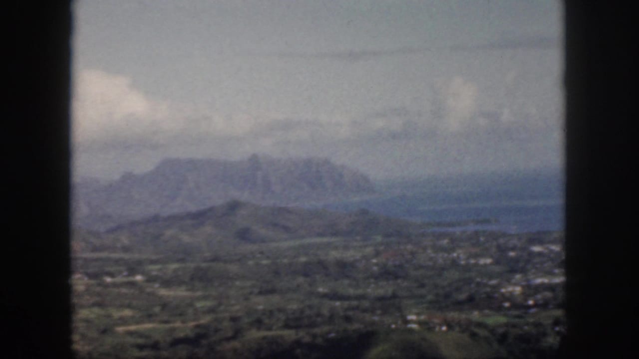 Mountain range and green valley visible between dark window mullions.
