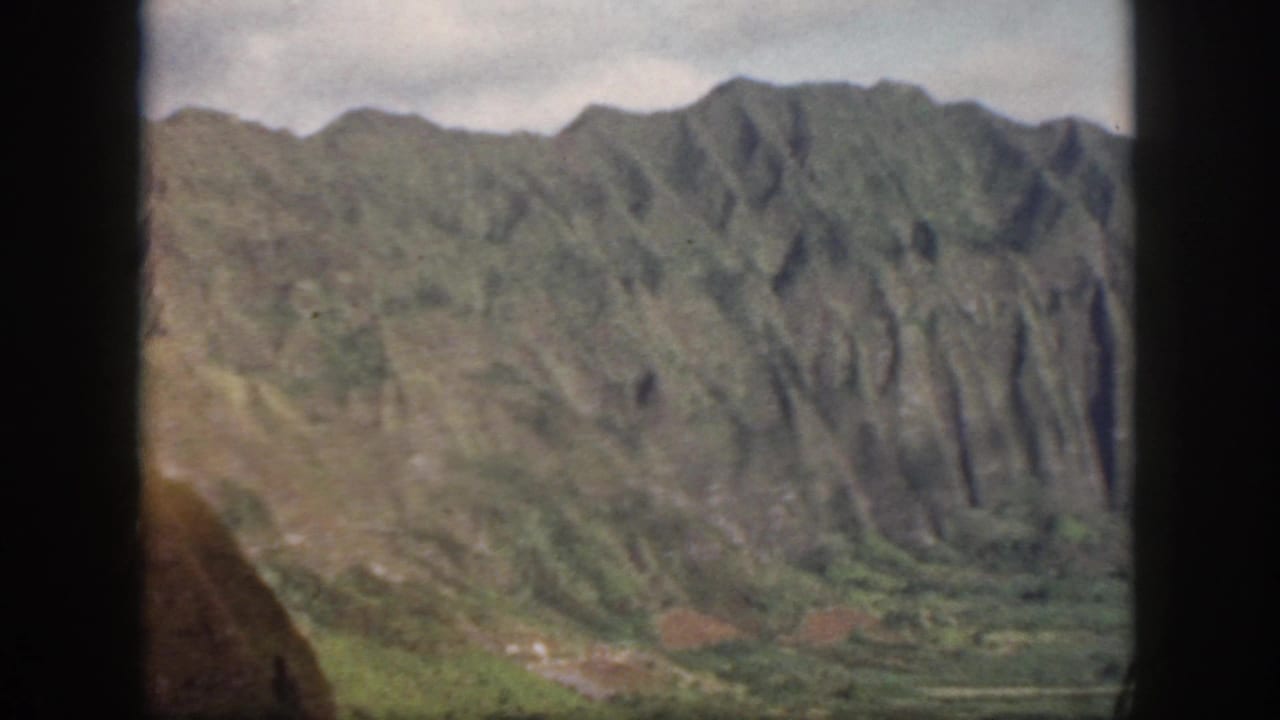 Oahu mountain landscape in a 1959 8mm frame, with ridged slopes, valley greenery, and contact-sheet borders visible.