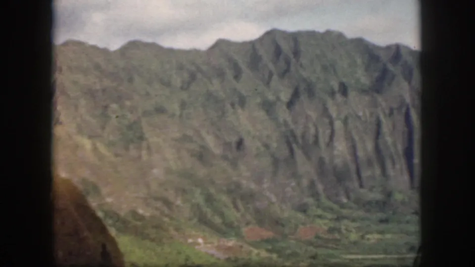 Oahu mountain landscape in a 1959 8mm frame, with ridged slopes, valley greenery, and contact-sheet borders visible.
