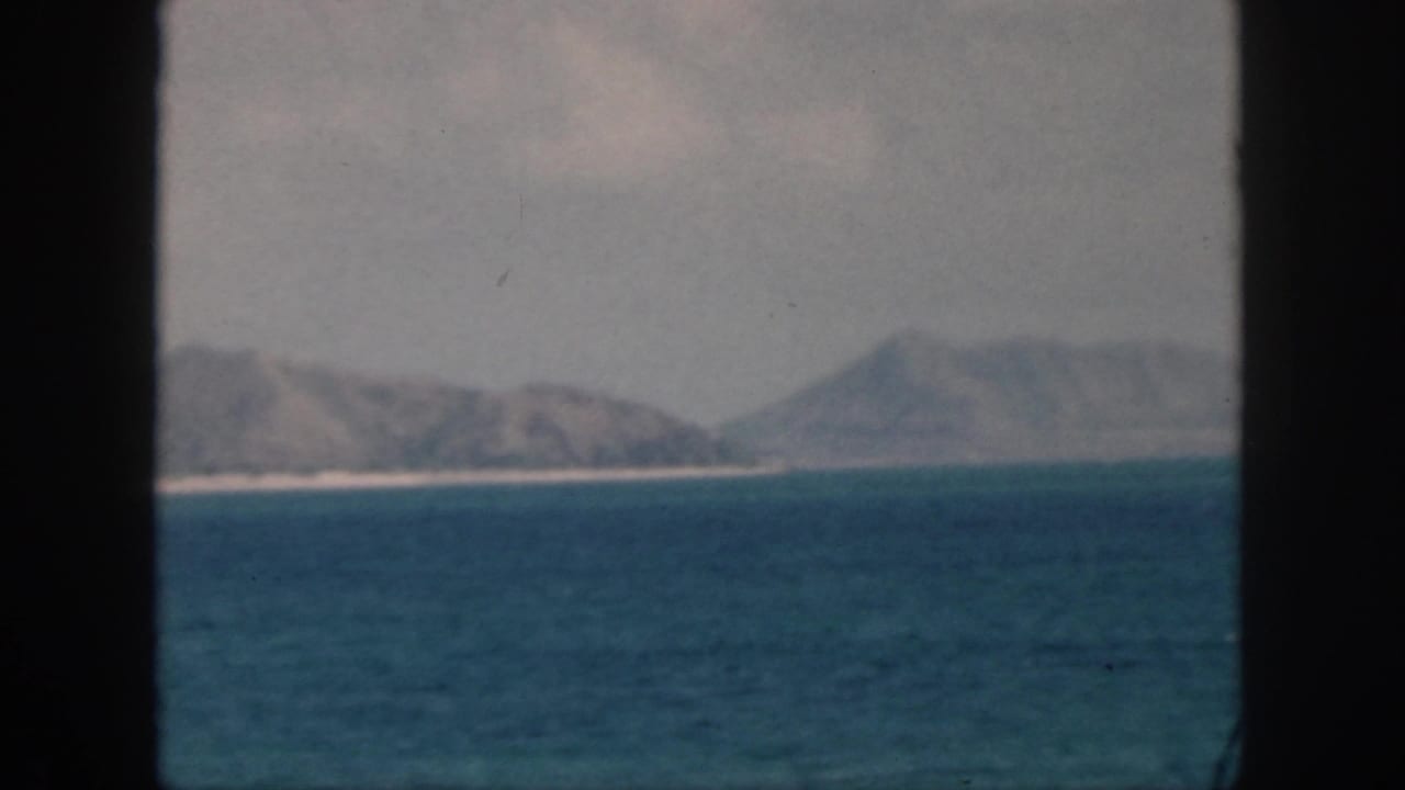Distant coastal hills across blue water, framed by dark vertical edges.