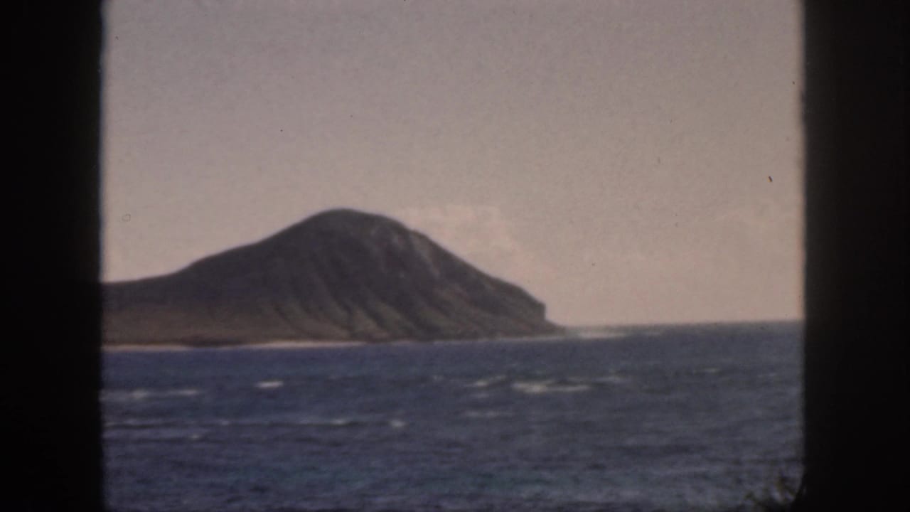 Island ridge across the ocean with whitecaps and dark frame borders at the sides.