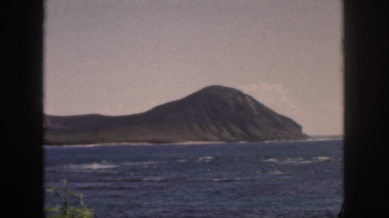 Ocean view toward a rounded island, bordered by dark window or door edges.