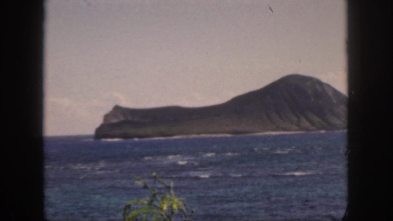 Rugged island and blue ocean with dark foreground frame edges.