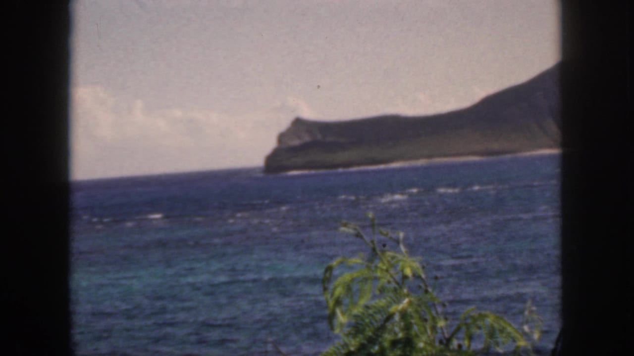 Ocean and low island coastline framed by dark vertical bars.