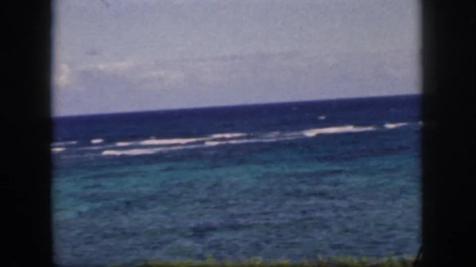 1959 Oahu coastal water view with turquoise shallows, darker blue sea, white reef surf, and dark window edges.