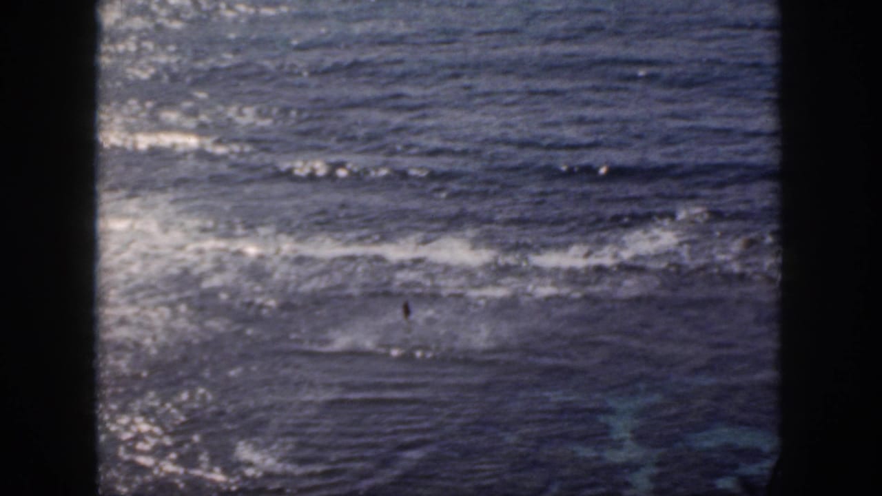 Open ocean with bright wave patterns and dark vertical film-frame borders.