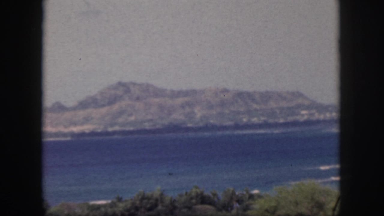 Ocean and hilly coastline framed by dark vertical window bars.