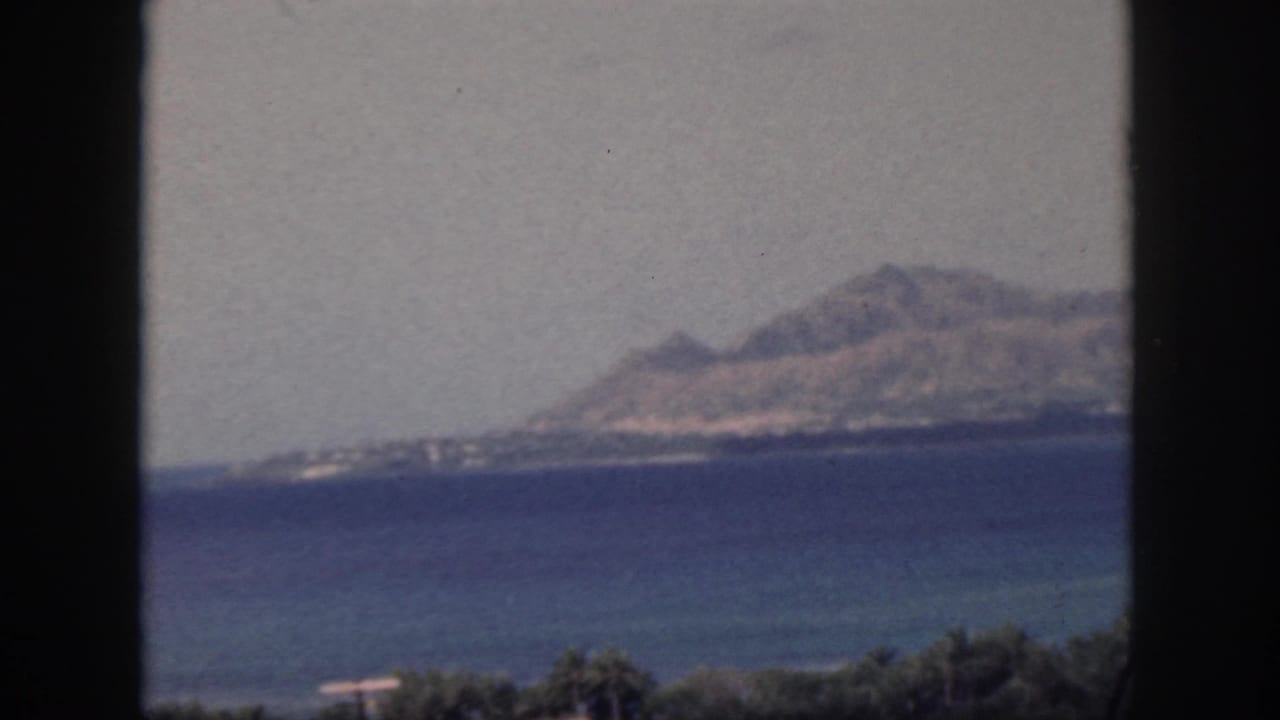 Island shoreline and mountain profile across water, divided by a dark window mullion.