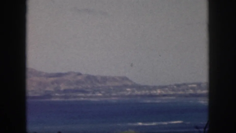 1959 Oahu 8mm frame with blue water in the foreground and low mountains along the far shore.