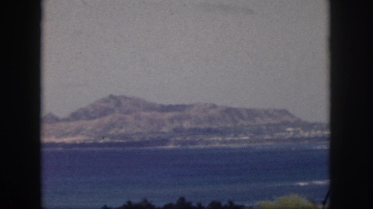Blue water and a distant mountain ridge framed by dark vertical edges.