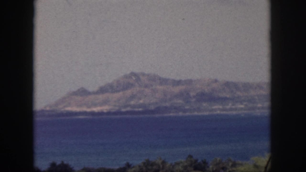 Sunlit mountain across a bay with dark framing at both sides.