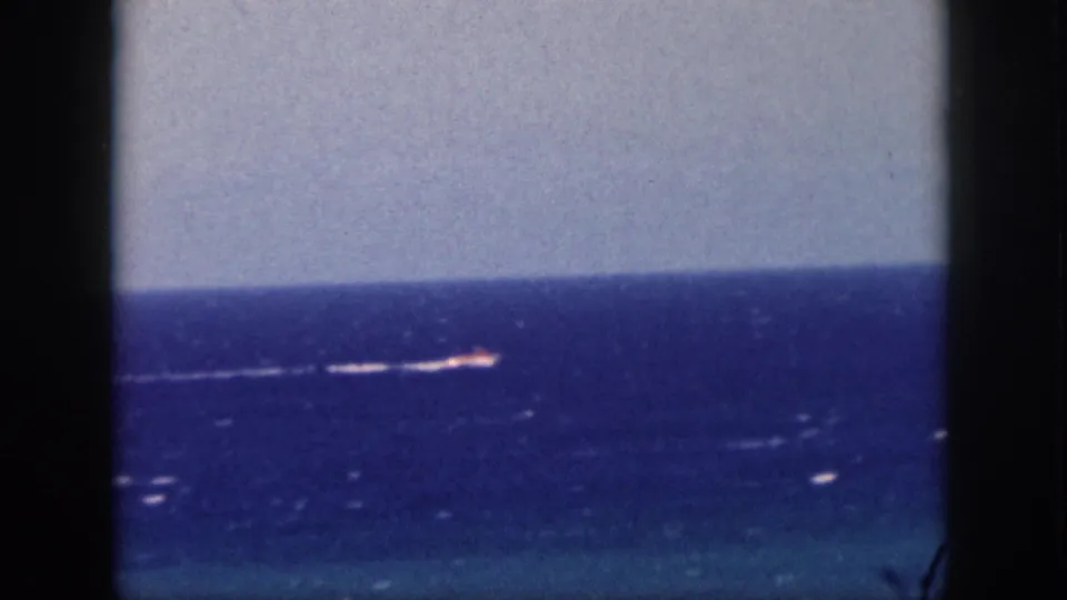 A 1959 Hawaii ocean view through a window, with a small distant vessel and wake near the horizon.