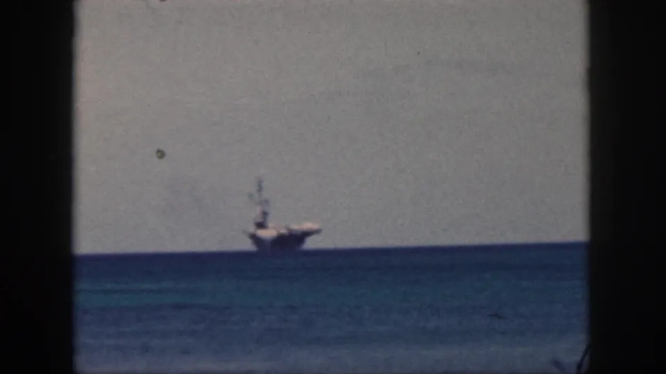 Oahu, 1959 home-movie view of a distant large vessel on the horizon, partially framed by a dark vertical window edge.