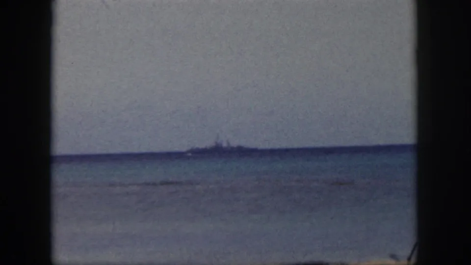 1959 Oahu coastal view with a low, distant ship silhouette across calm water under a pale sky.