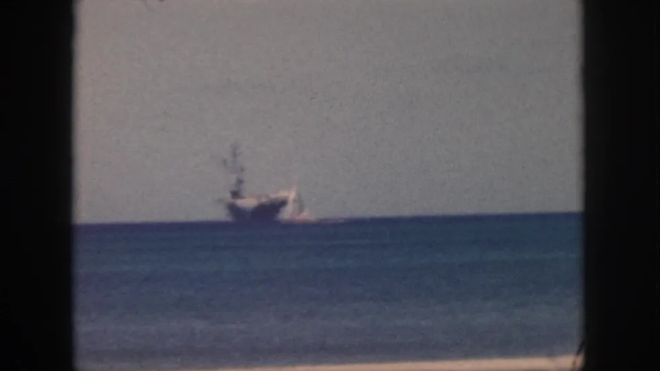 1959 Oahu 8mm frame with a large distant ship and small sailboat seen across open water.