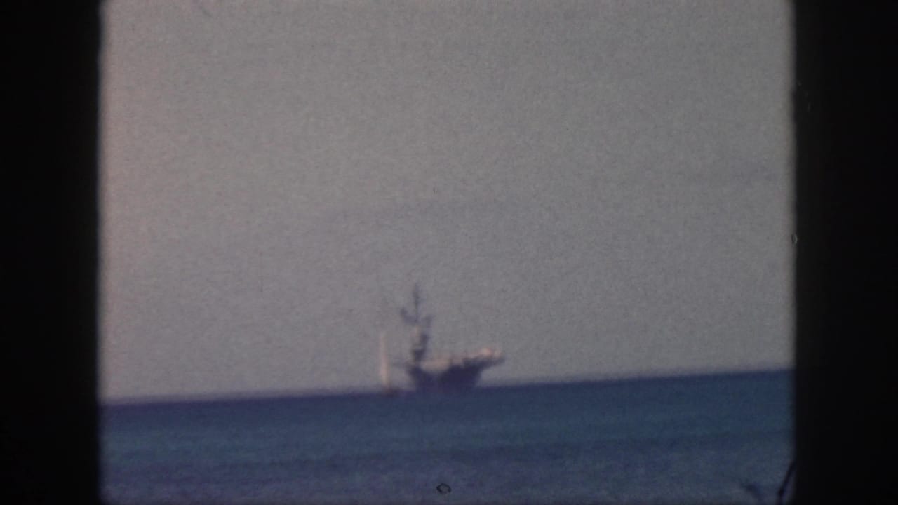 Large distant vessel near the horizon, framed by dark film edges.