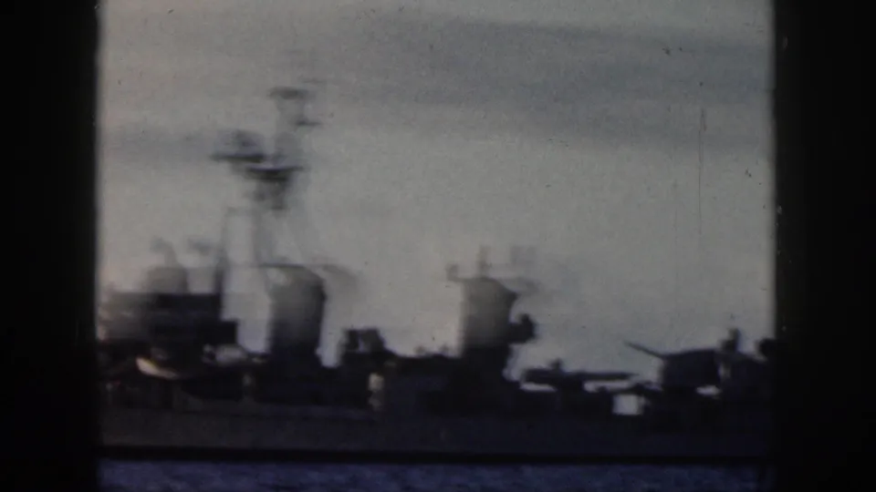 Military-style vessel on Oahu waters, with masts and equipment silhouetted against a cloudy sky in 8mm footage.