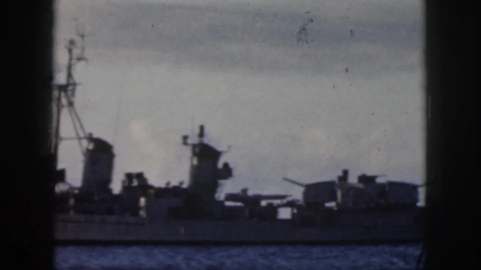 Side view of a naval-looking vessel with radar or communications gear on Oahu waters, framed by dark foreground edges.