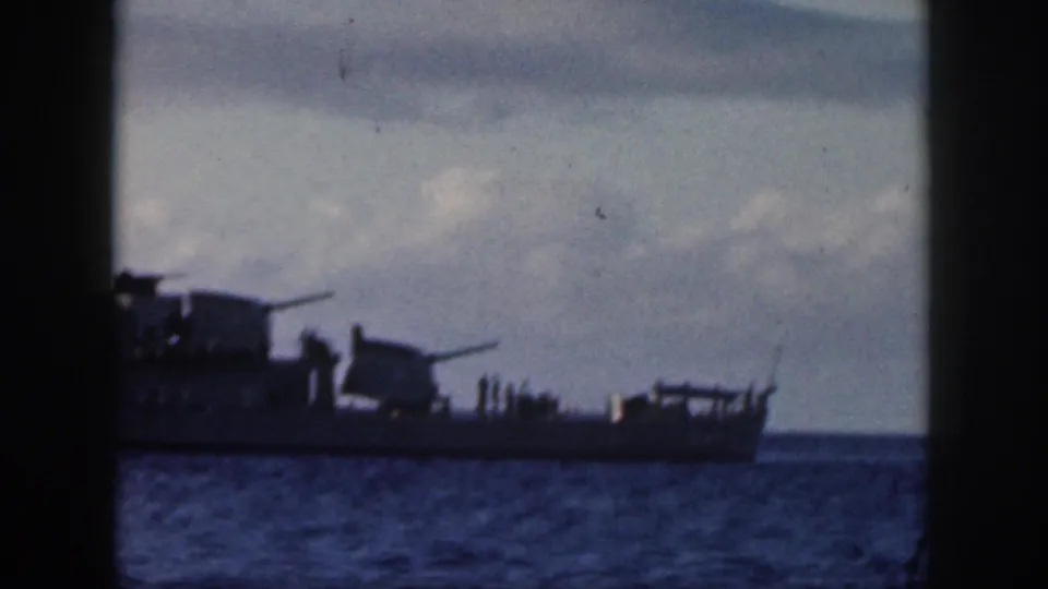 1959 Oahu 8mm frame showing a U.S. Navy warship silhouetted on calm water through dark foreground framing.