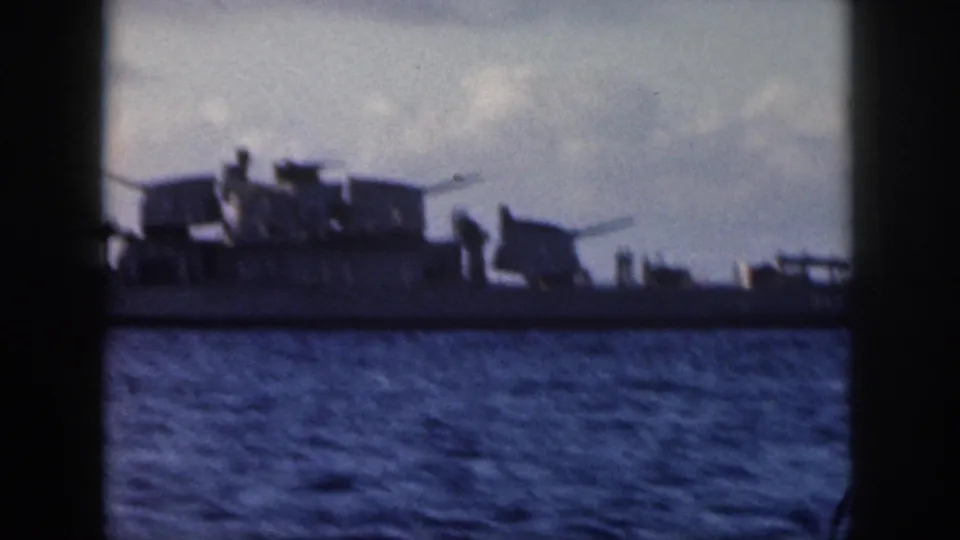1959 Oahu 8mm frame with a closer view of a U.S. Navy warship, deck guns, mast equipment, and small crew figures.