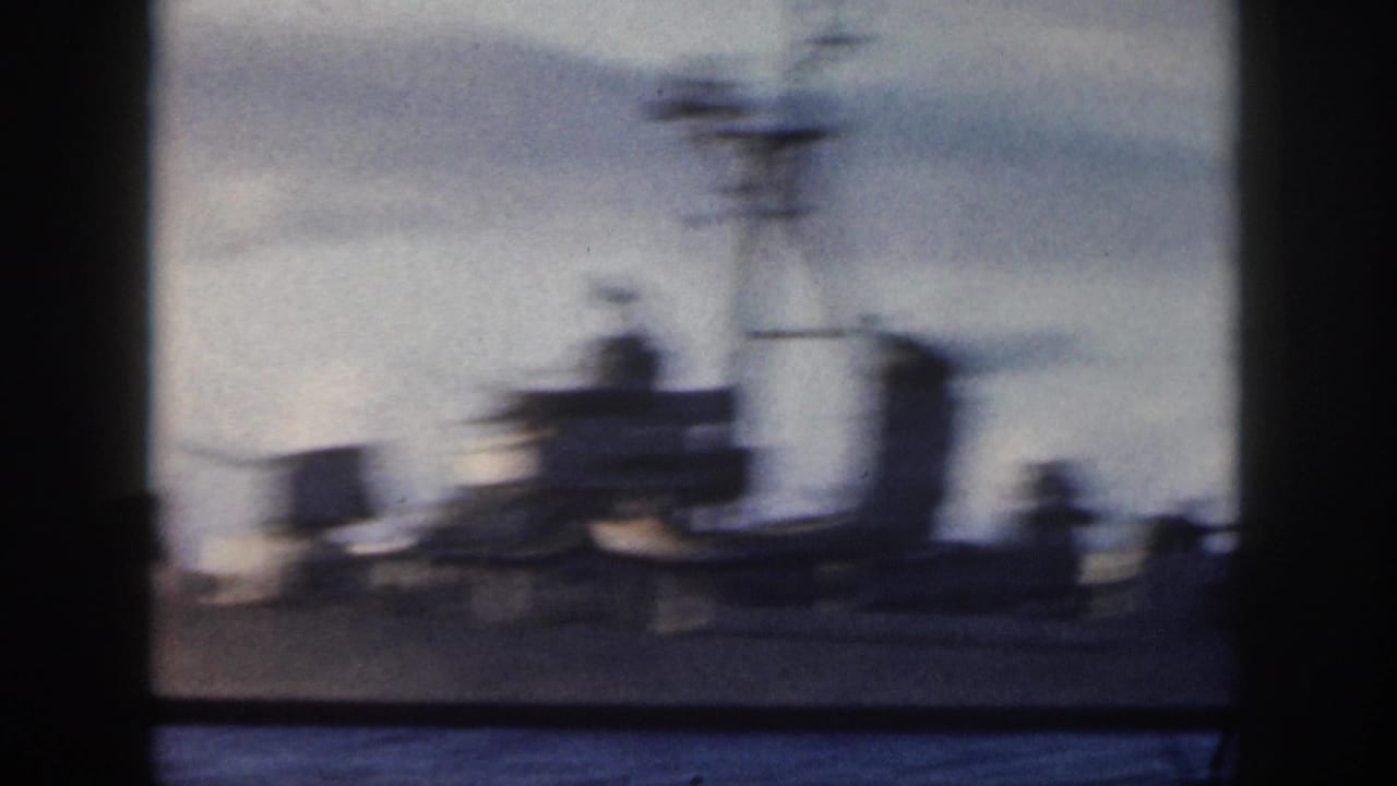 Soft 1959 Oahu home-movie frame of a gray U.S. Navy warship passing offshore, partly blurred and bordered by dark vertical edges.