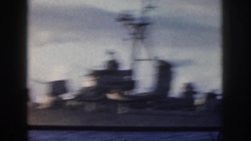 Soft 1959 Oahu home-movie frame of a gray U.S. Navy warship passing offshore, partly blurred and bordered by dark vertical edges.