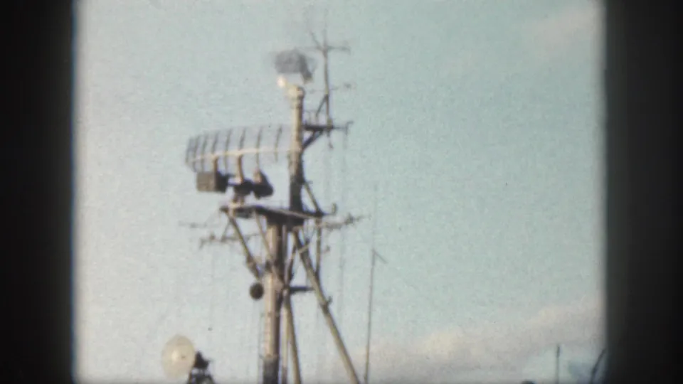 1959 Oahu home-movie frame showing radar equipment and antennas on a military ship at sea.