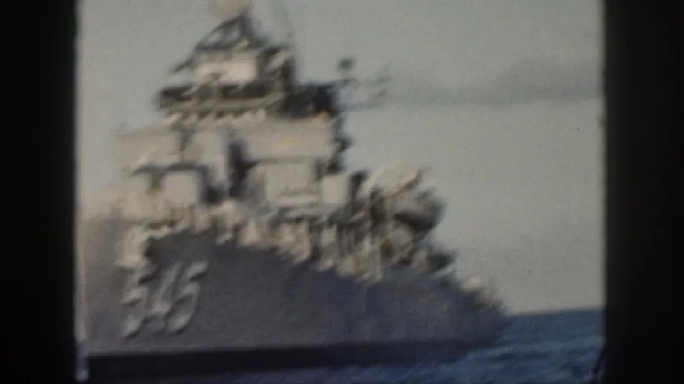 Color 8mm frame from the 1959 Oahu clip showing destroyer 545 at sea from a bow-side angle, with mast, bridge and deck equipment softened by motion blur.