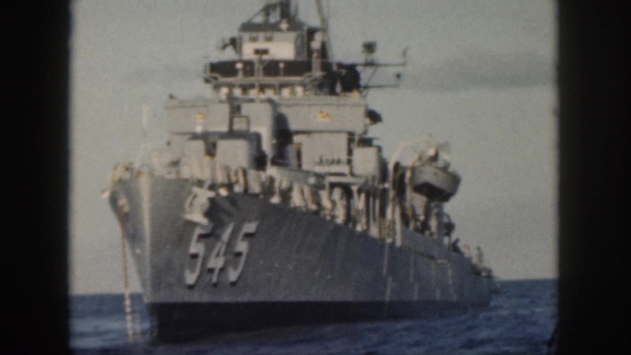 1959 Oahu home-movie frame showing a gray U.S. Navy ship marked 545 approaching across open water.