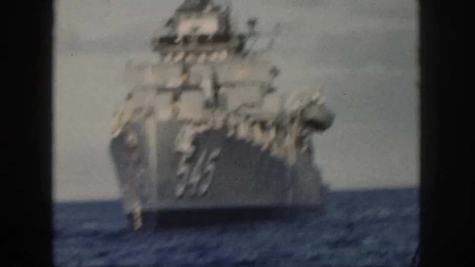 Blurred 8mm frame of the gray U.S. Navy ship marked 545 moving across open water near Oahu.