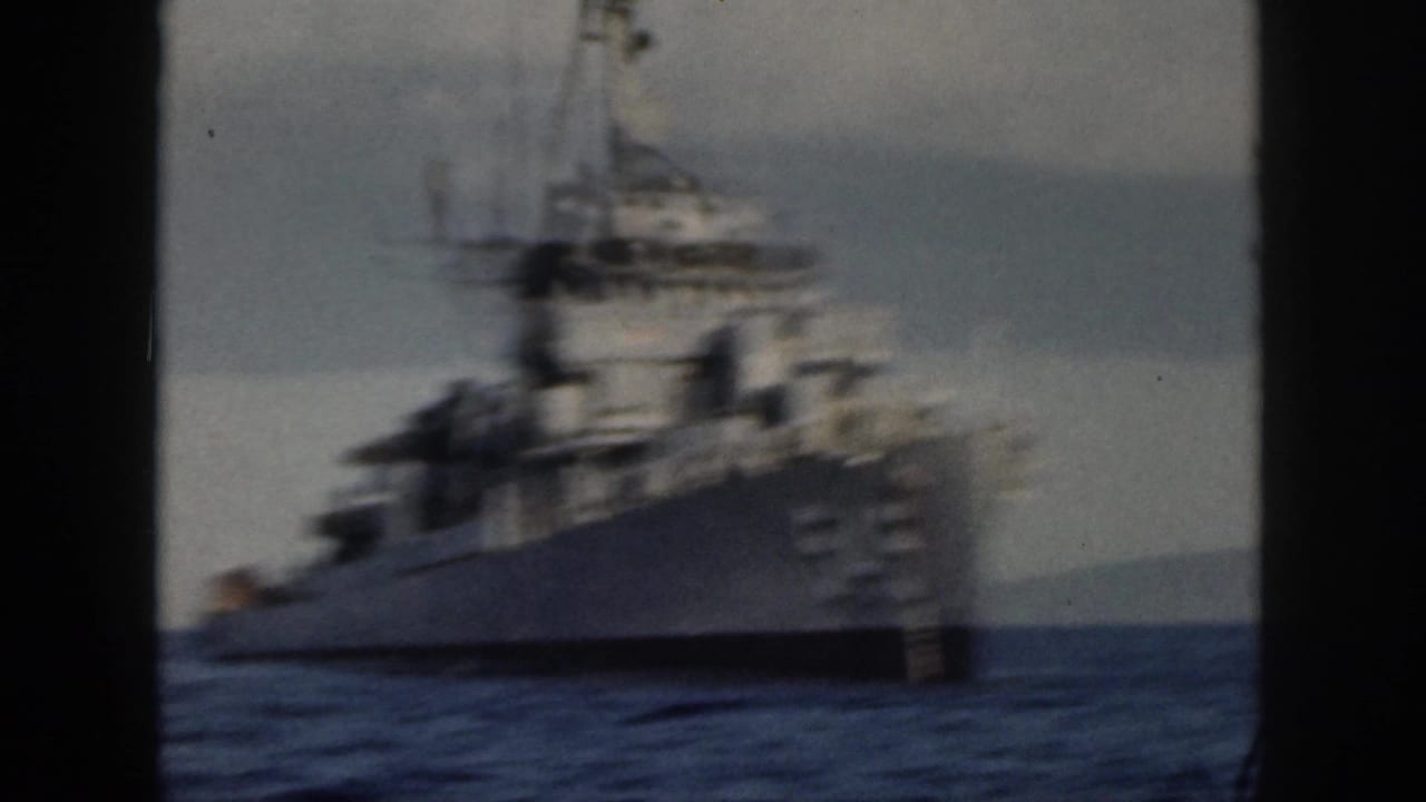 1959 Oahu home-movie frame showing a gray U.S. Navy destroyer at sea, viewed obliquely with soft focus and visible film grain.