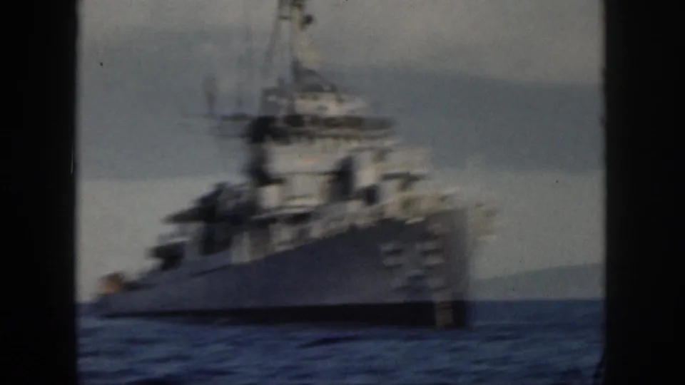 1959 Oahu home-movie frame showing a gray U.S. Navy destroyer at sea, viewed obliquely with soft focus and visible film grain.
