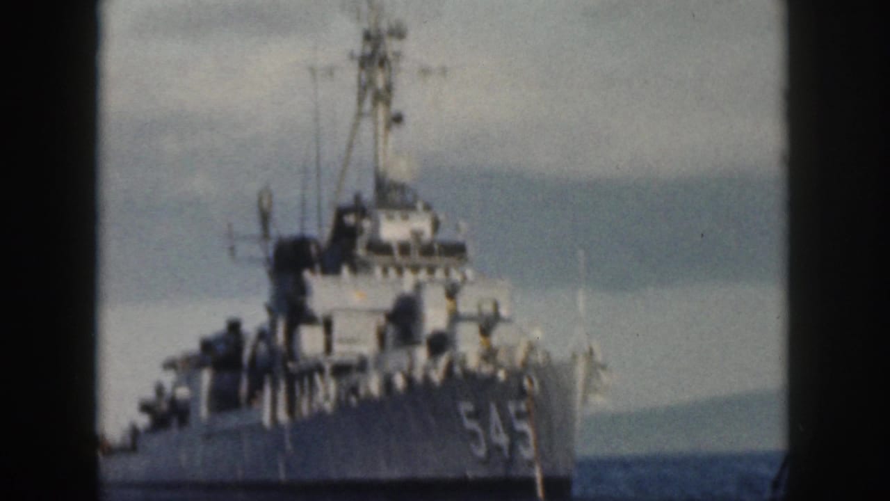 1959 Oahu frame showing the bow of a U.S. Navy destroyer marked 545, with mast, deck fittings, and sea visible around it.