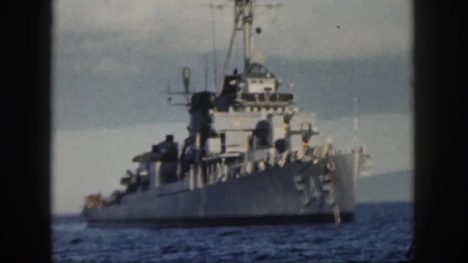 1959 Oahu home-movie view of a gray U.S. Navy destroyer underway, with hull number 545 and superstructure visible through soft 8mm focus.