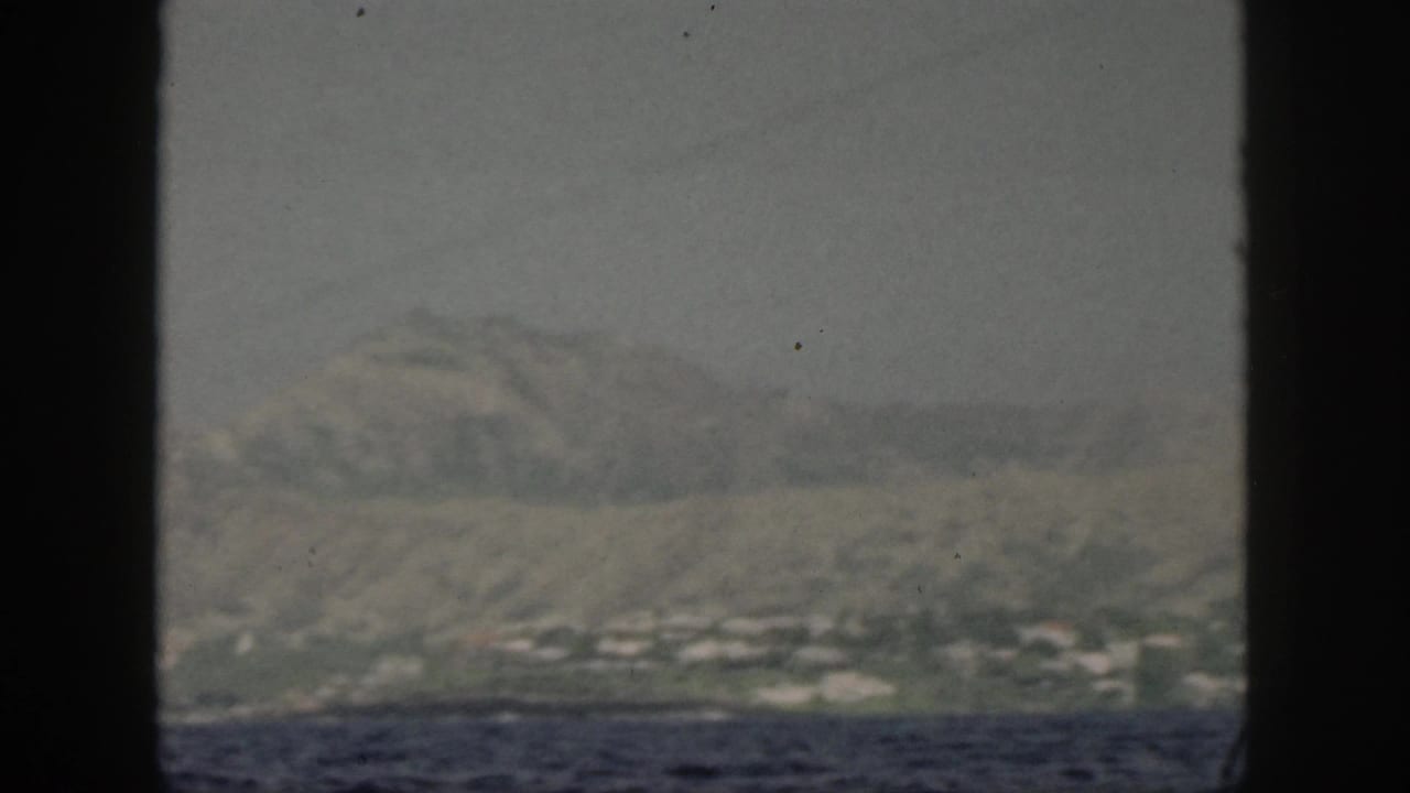 Distant coastal town and mountain slope viewed across the ocean.