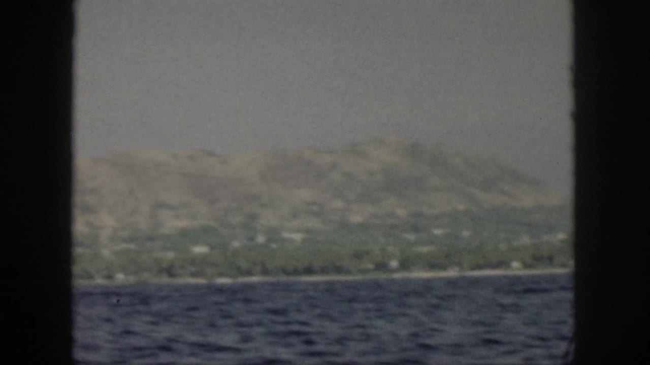 Distant green shoreline and hills behind choppy water, partly blocked by dark frame borders.