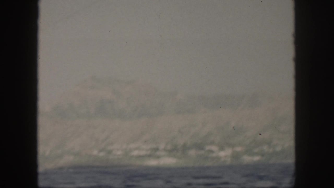 Soft 8mm view of the sea off Oahu in the 1959 home-movie clip, framed by dark boat structure.