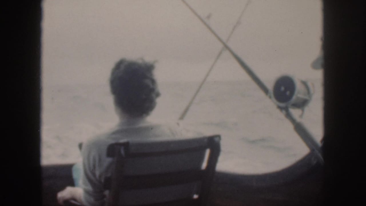 Seated woman faces open water with fishing rods and a reel visible on the boat.