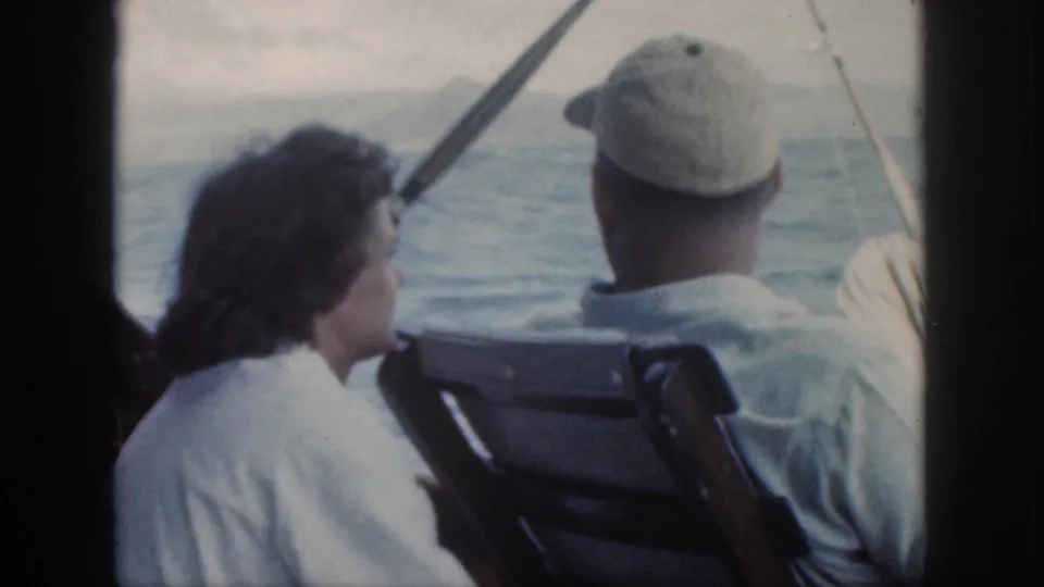 A woman with dark hair sits beside a man in a cap as they look out over the water during an Oahu boat ride.