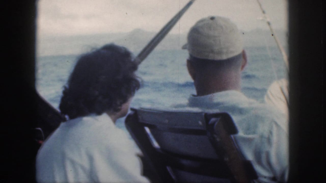 Adults on a boat look out over rough ocean water with rods nearby.