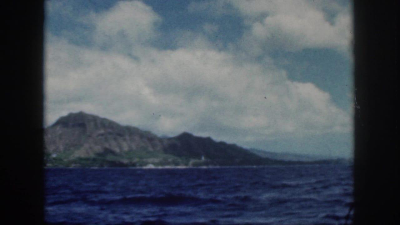 1959 8mm view from a boat toward Oahu's volcanic mountains and shoreline across deep blue ocean.