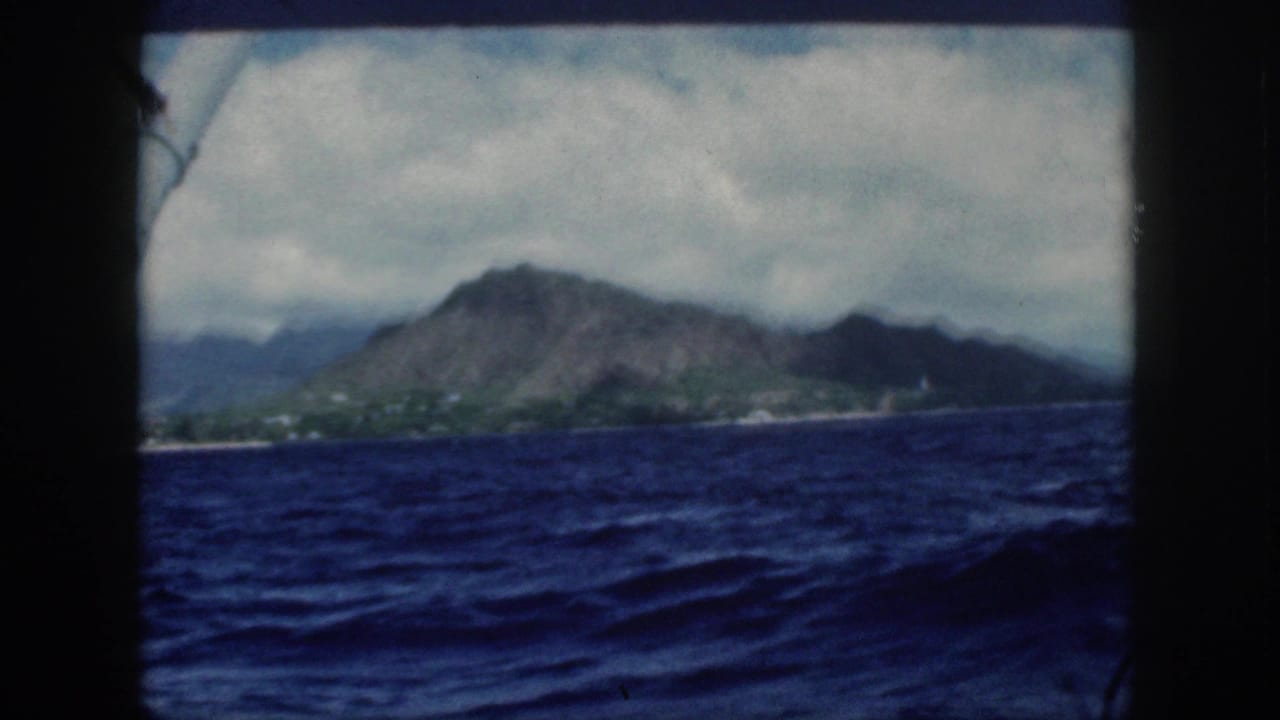 Ocean foreground with Oahu mountains and shoreline seen through a dark frame.
