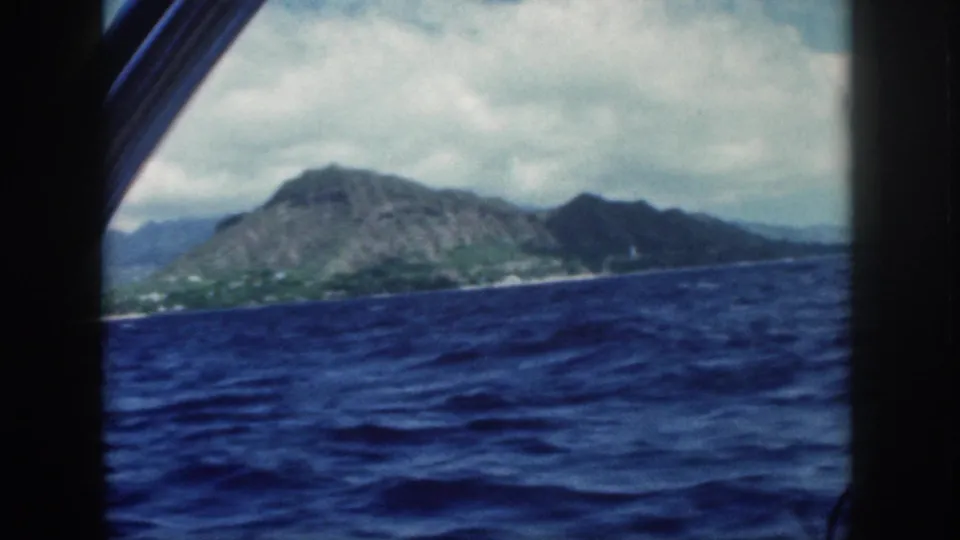 1959 Oahu boat view with Diamond Head and coastline beyond dark window framing and choppy blue water.