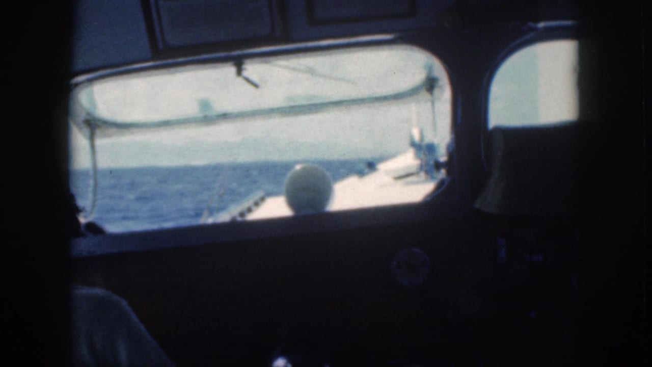 Forward boat cabin view with ocean outside and a person partly visible in shadow at left.