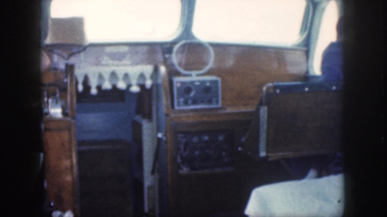 Boat cabin dashboard and helm seating with bright windows and wood trim.