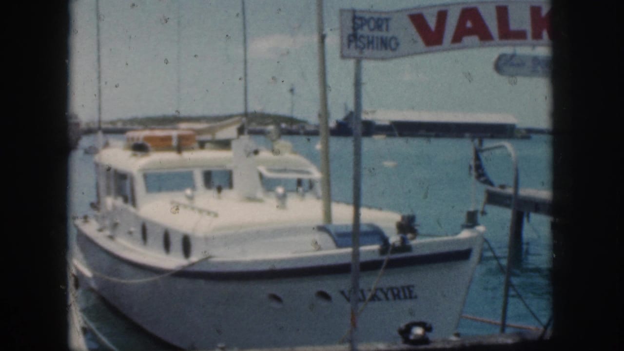 Vintage 8mm frame from Oahu showing the Valkyrie cabin motorboat docked under harbor signage in 1959.