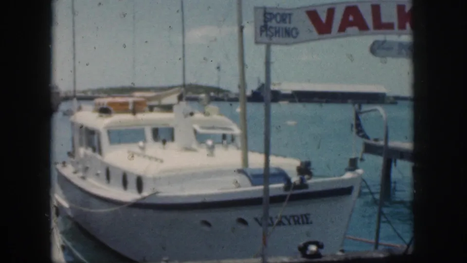 Vintage 8mm frame from Oahu showing the Valkyrie cabin motorboat docked under harbor signage in 1959.