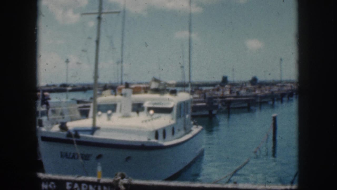 1959 Oahu home-movie frame with the VALKYRIE cabin cruiser framed close to the dock in a marina setting.