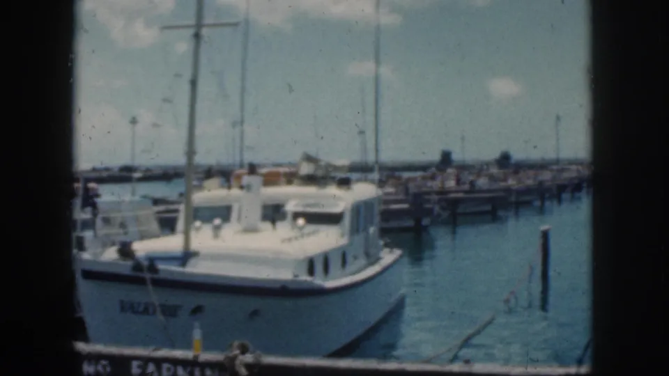 1959 Oahu home-movie frame with the VALKYRIE cabin cruiser framed close to the dock in a marina setting.