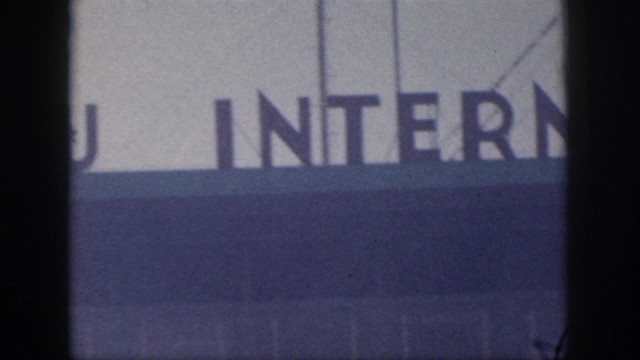 The pan reveals part of the word INTERNATIONAL on a large outdoor airport sign in metadata-supported 1959 Oahu footage.